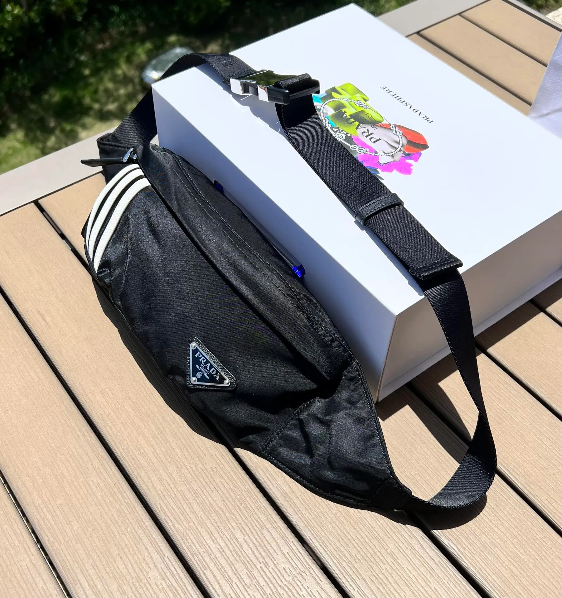可調式尼龍腰帶和側面插扣,拉鍊開合琺瑯金屬三角形徽標與adidas Re -Nylon 徽標