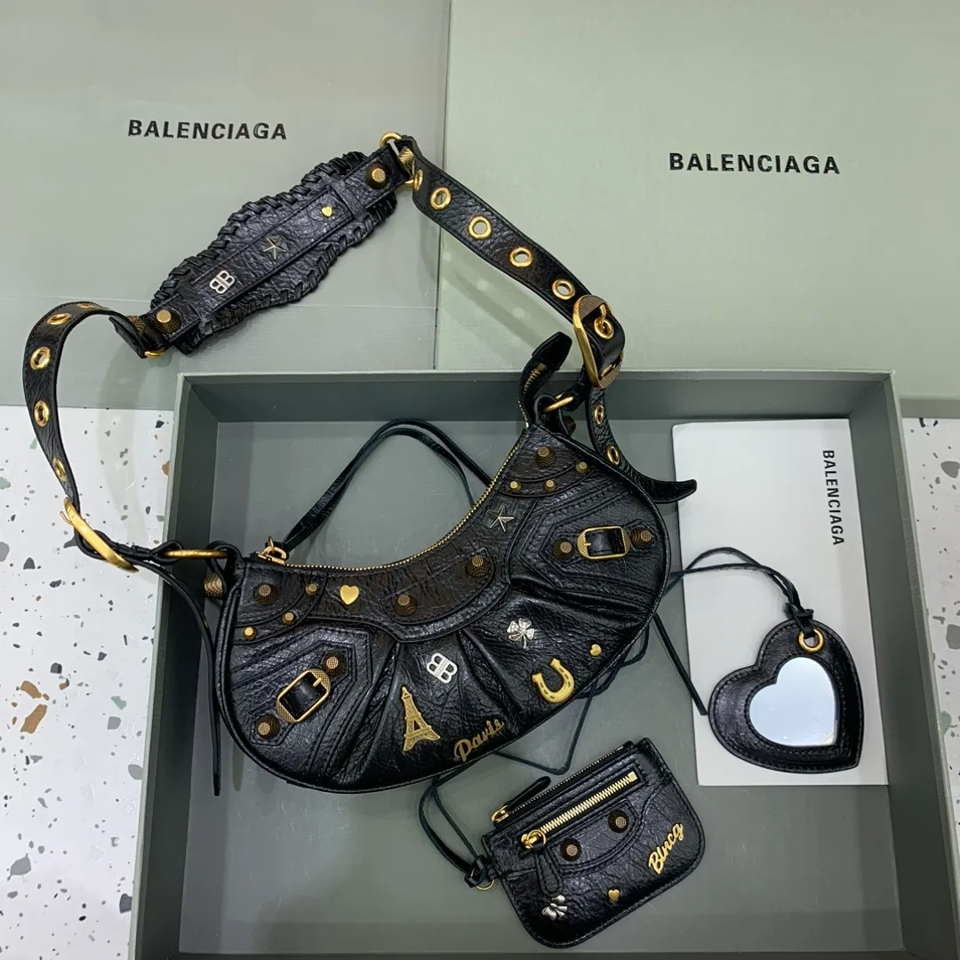 【小號】油臘黑掛飾Balenciag Le Cagole半月牙腋下包斜挎包致敬經典機車包系列重磅新款王炸登場la～在傳統的機車包上做了改良 可調節編織肩帶附加孔眼和外掛皮革卡包、心型掛鏡♡沿用經典機車元素 細節非常講究 上身簡直痴迷復古率性 充滿搖滾氣息的大膽與前衛 辣妹本辣必須人手一個 愛了！