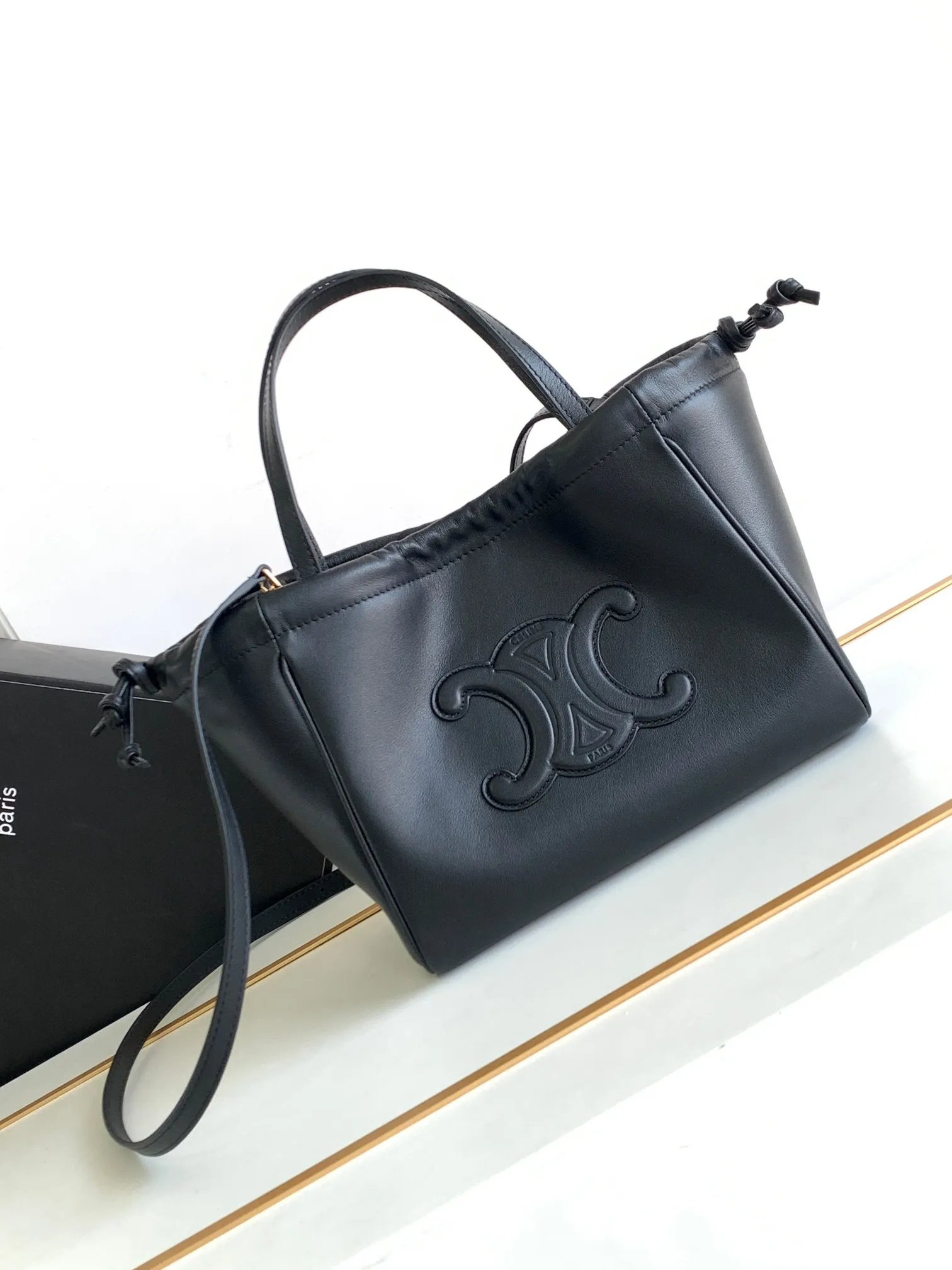 CELINE｜小號光滑牛皮革抽繩包💛最新MINI CUIR CABAS早春新品「全皮浮雕凱旋門Mini tote」經典黑色～四季百搭 小號可可愛愛 柔軟牛皮質感滿分 摸起來手感簡直無敵 想要大容量包包的姐妹閉眼衝👏日常的雨傘、手機、水杯、化妝品隨便裝牛皮革，翻毛牛皮革襯裡，可手提、肩背和斜挎，裝飾性抽繩，搭配可拆卸和可調節肩帶，最小長度45厘米，最大長度54厘米尺寸：22x17x15厘米型號：111013