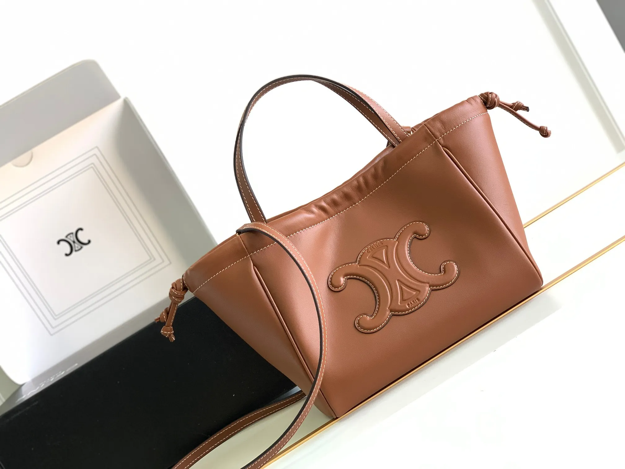 CELINE｜小號光滑牛皮革抽繩包💛最新MINI CUIR CABAS早春新品「全皮浮雕凱旋門Mini tote」復古焦糖色～四季百搭 小號可可愛愛 柔軟牛皮質感滿分 摸起來手感簡直無敵 想要大容量包包的姐妹閉眼衝👏日常的雨傘、手機、水杯、化妝品隨便裝牛皮革，翻毛牛皮革襯裡，可手提、肩背和斜挎，裝飾性抽繩，搭配可拆卸和可調節肩帶，最小長度45厘米，最大長度54厘米尺寸：22x17x15厘米型號：111013